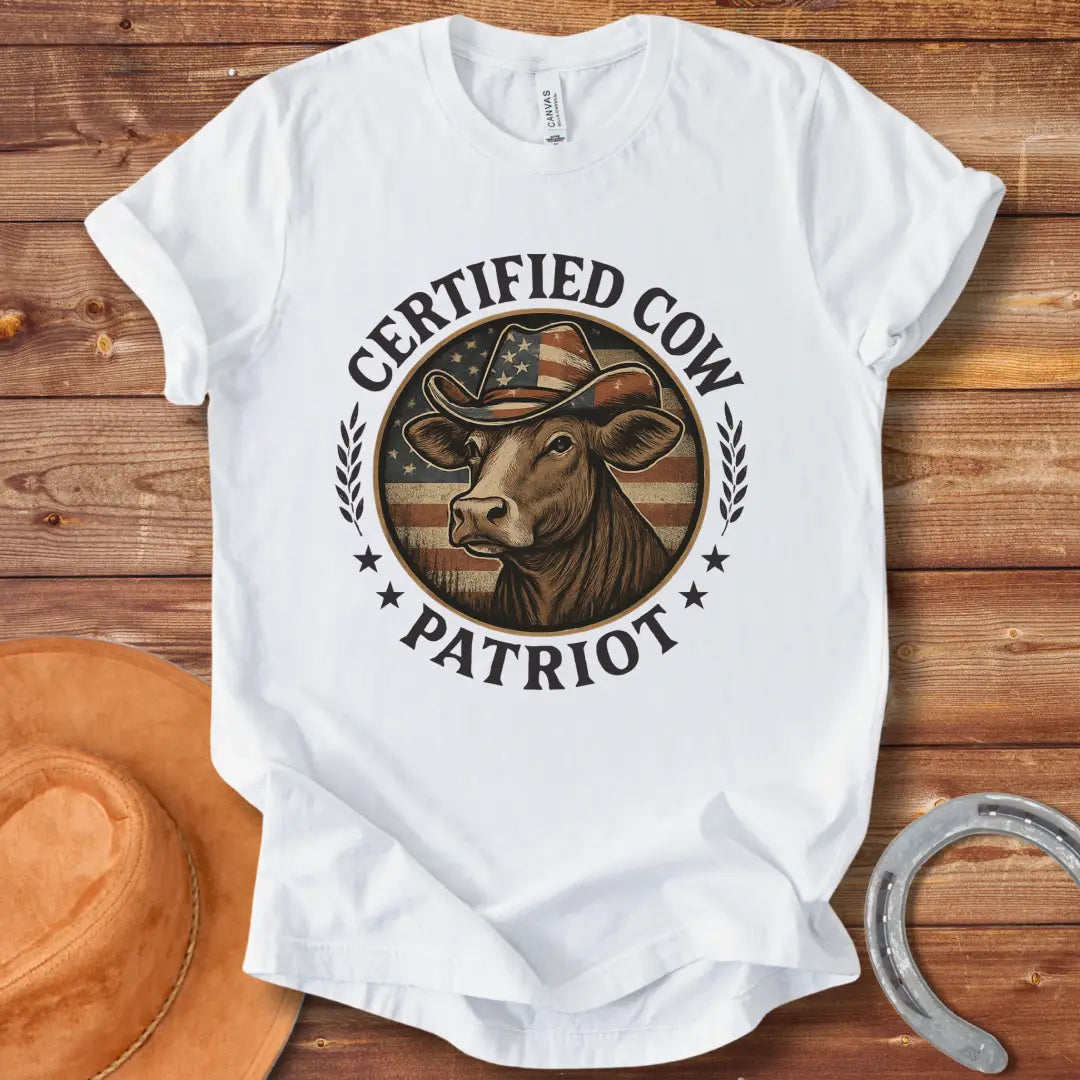 Certified Cow Patriot T-Shirt featuring a cow wearing an American flag cowboy hat, surrounded by stars and wheat stalks.