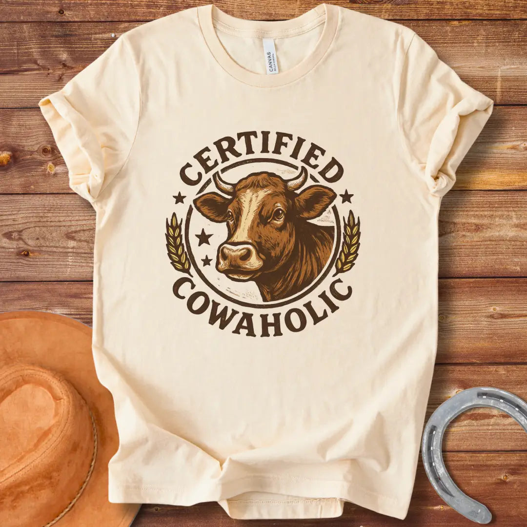 Certified Cowaholic T-shirt design featuring a cow's head in a circular badge, surrounded by text and wheat stalks.