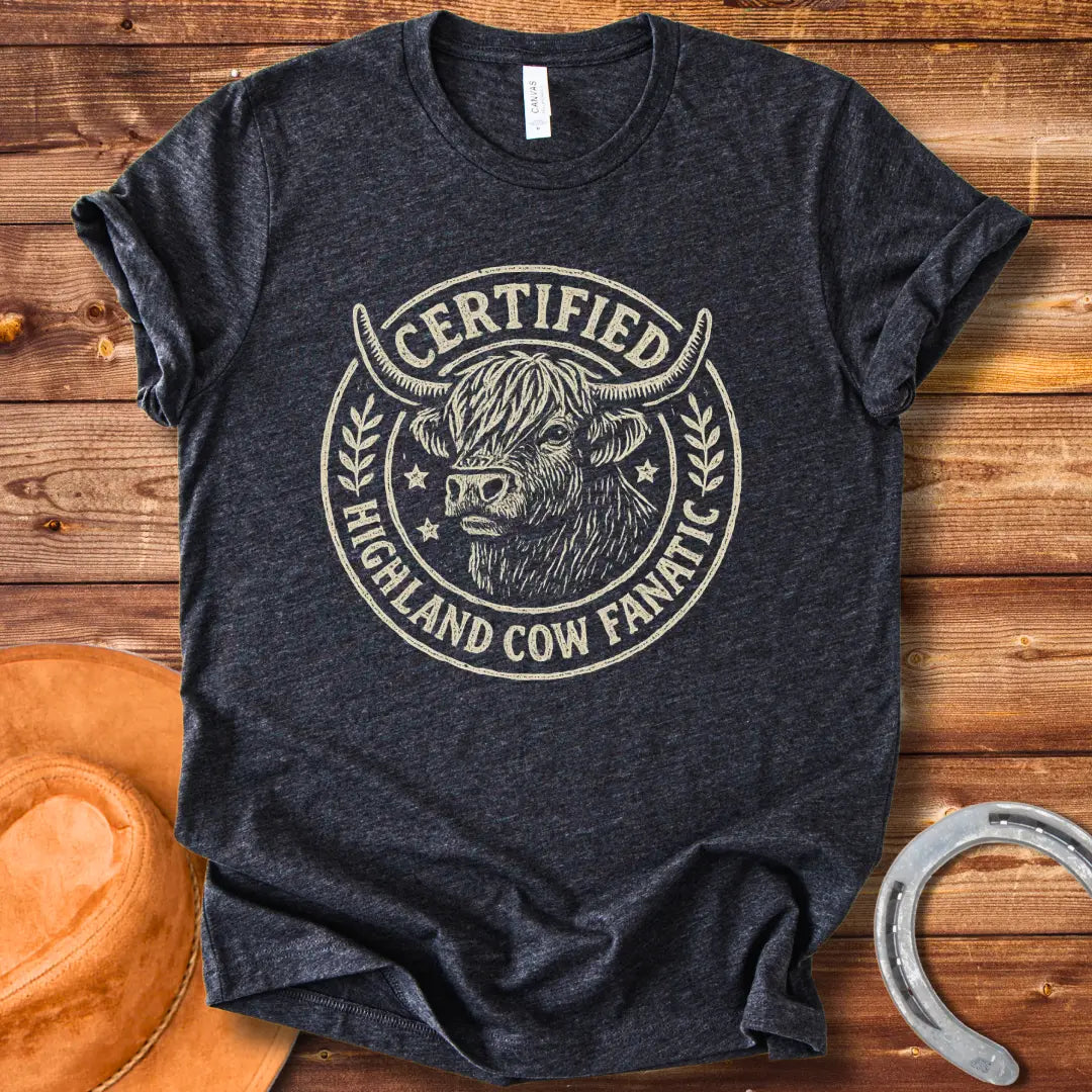 Certified Highland Cow Fanatic T-Shirt design, featuring a detailed illustration of a Highland cow within a circular badge with text.