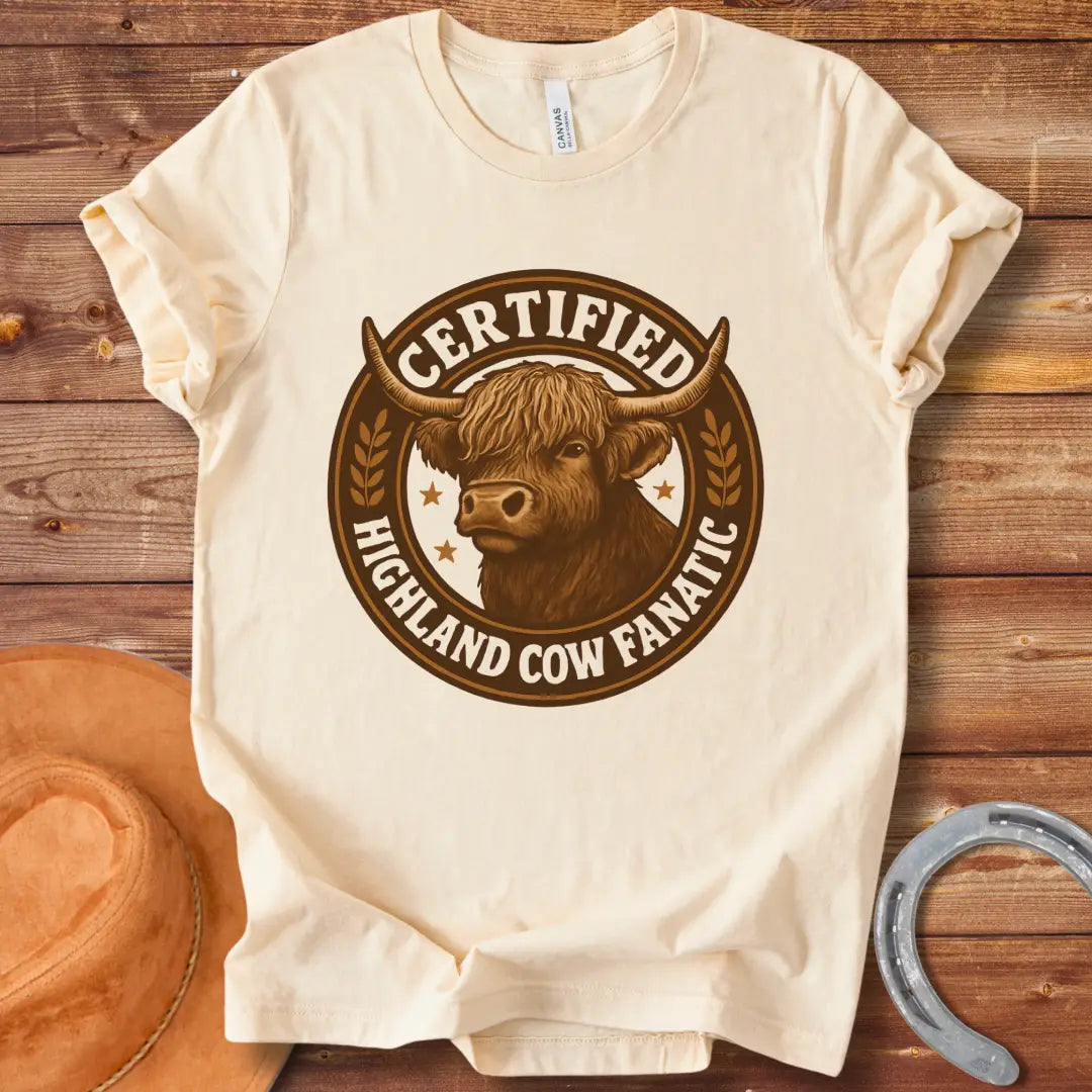 Certified Highland Cow Fanatic T-Shirt design, featuring a detailed illustration of a Highland cow within a circular badge with text.
