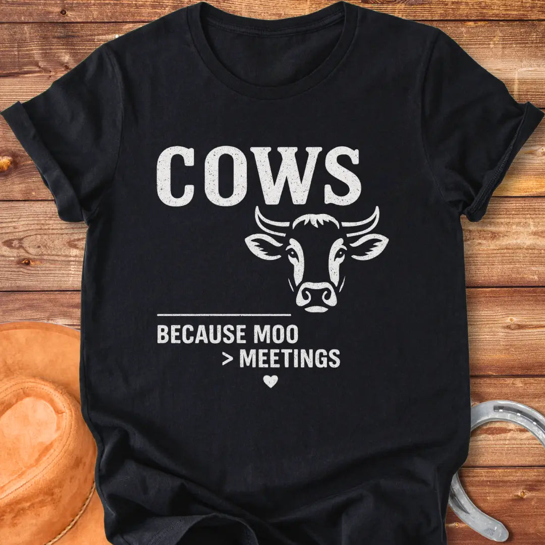 Black and white t-shirt design featuring a cow's face with the words Cows Because Moo Better Than Meetings