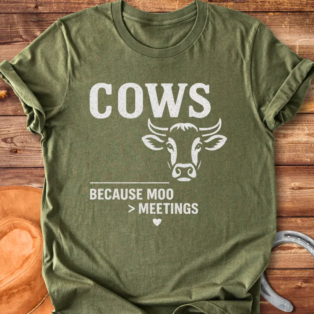 Black and white t-shirt design featuring a cow's face with the words Cows Because Moo Better Than Meetings