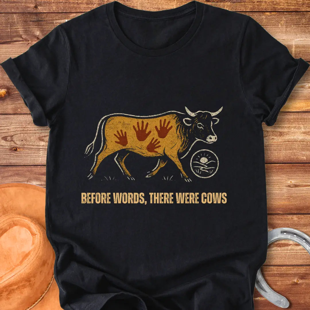 Vintage-style t-shirt design featuring a cow with handprints and the words "Before Words, There Were Cows."