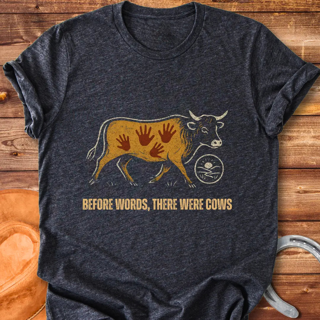 Vintage-style t-shirt design featuring a cow with handprints and the words "Before Words, There Were Cows."