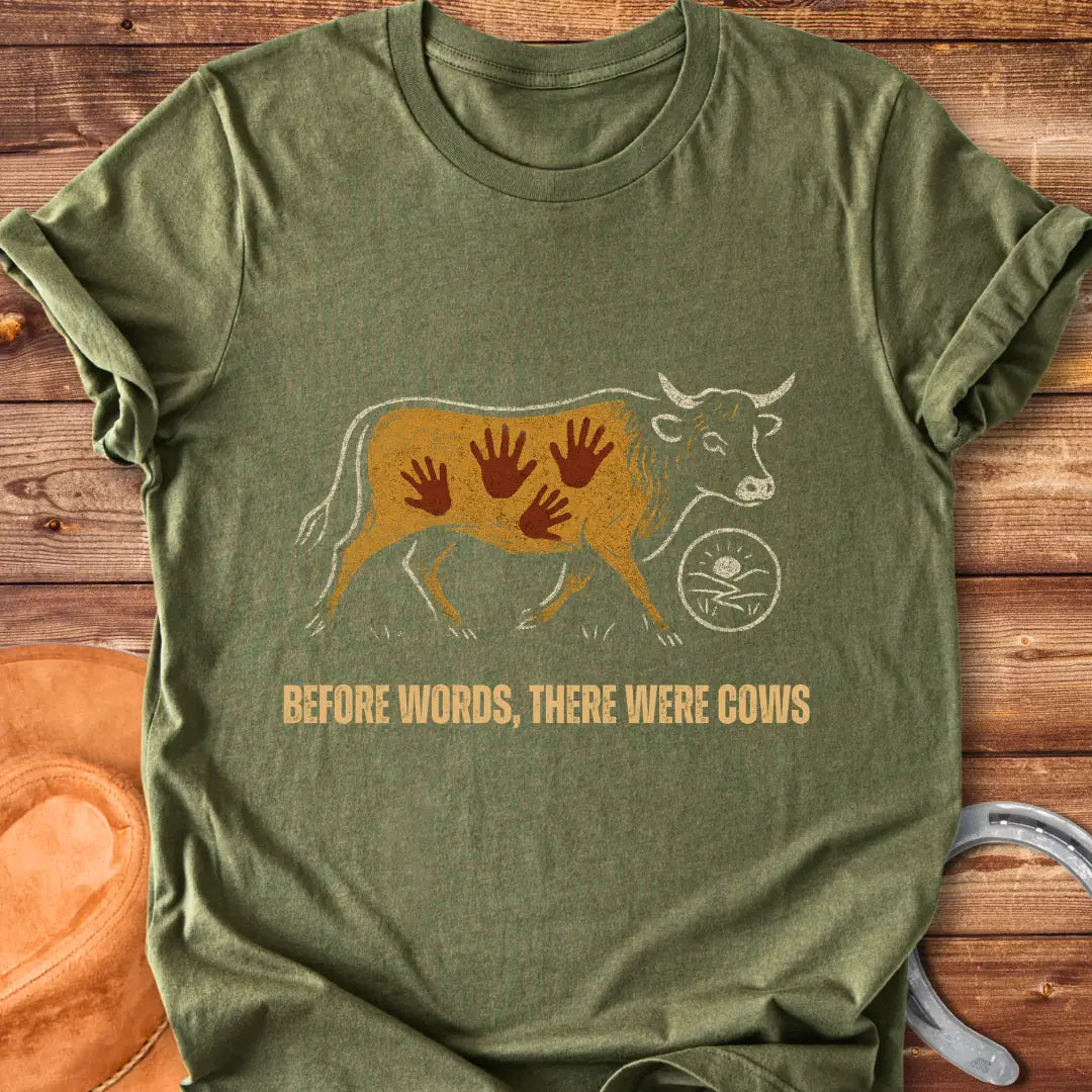 Vintage-style t-shirt design featuring a cow with handprints and the words "Before Words, There Were Cows."