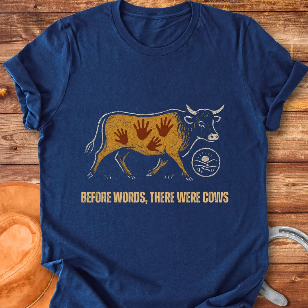 Vintage-style t-shirt design featuring a cow with handprints and the words "Before Words, There Were Cows."