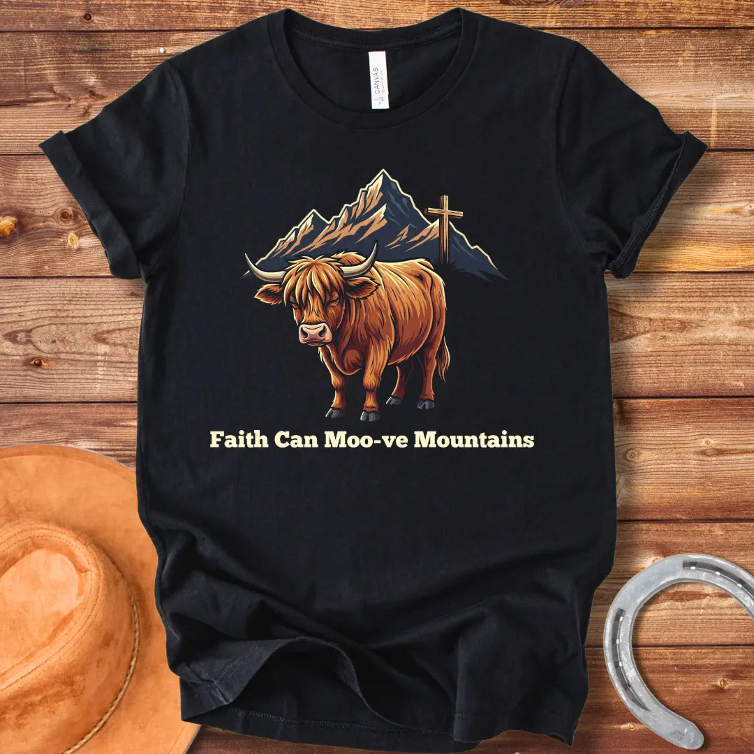 Highland cow graphic t-shirt with the words 'Faith Can Moo-ve Mountains', with mountain range and cross in the background