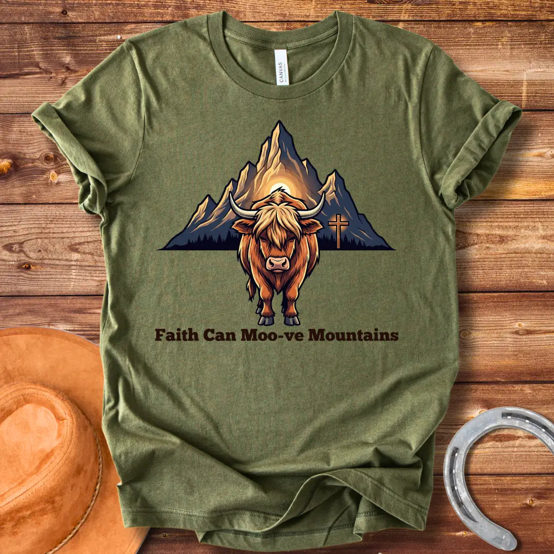 Highland cow graphic t-shirt with the words 'Faith Can Moo-ve Mountains', with mountain range and cross in the background