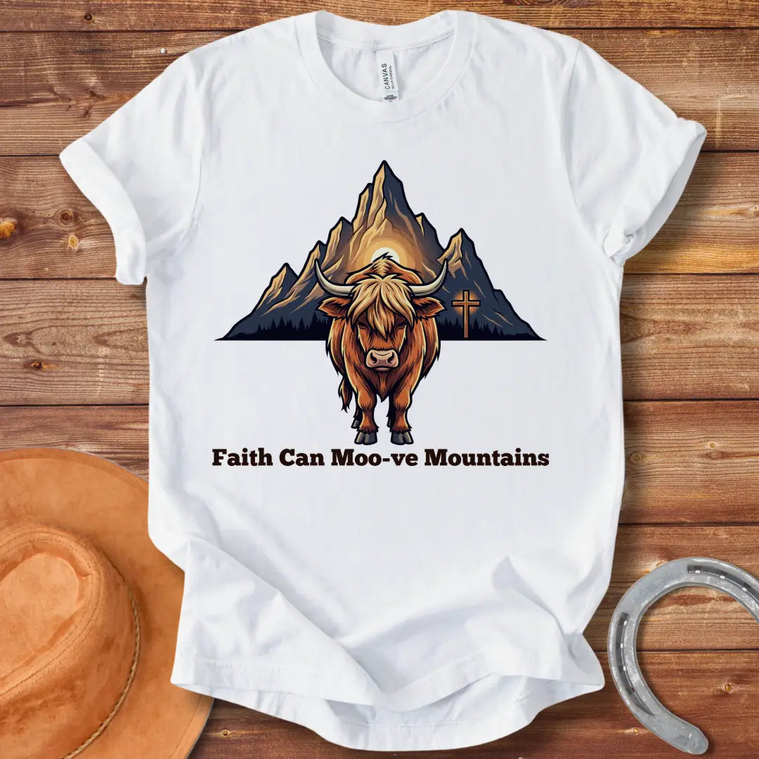 Highland cow graphic t-shirt with the words 'Faith Can Moo-ve Mountains', with mountain range and cross in the background