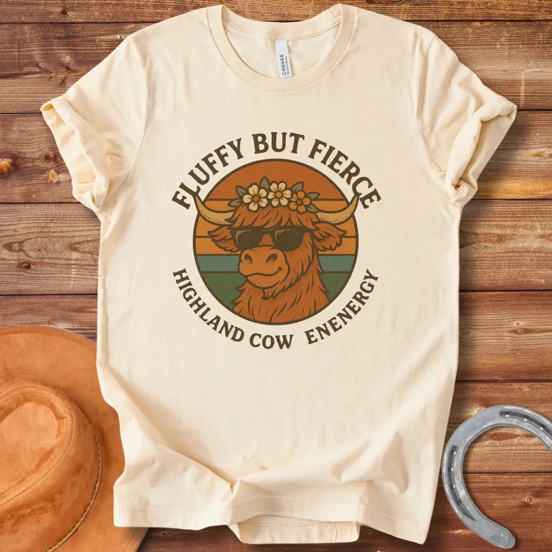 Fluffy but Fierce t-shirt featuring a Highland cow wearing sunglasses and a flower crown, with text reading 'Highland Cow Energy'