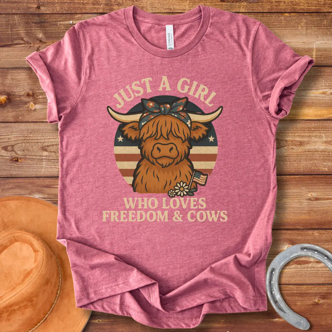 A cute Highland cow wearing a floral bandana, set against a patriotic American flag circle. Text reads 'Just a girl who loves freedom & cows'.