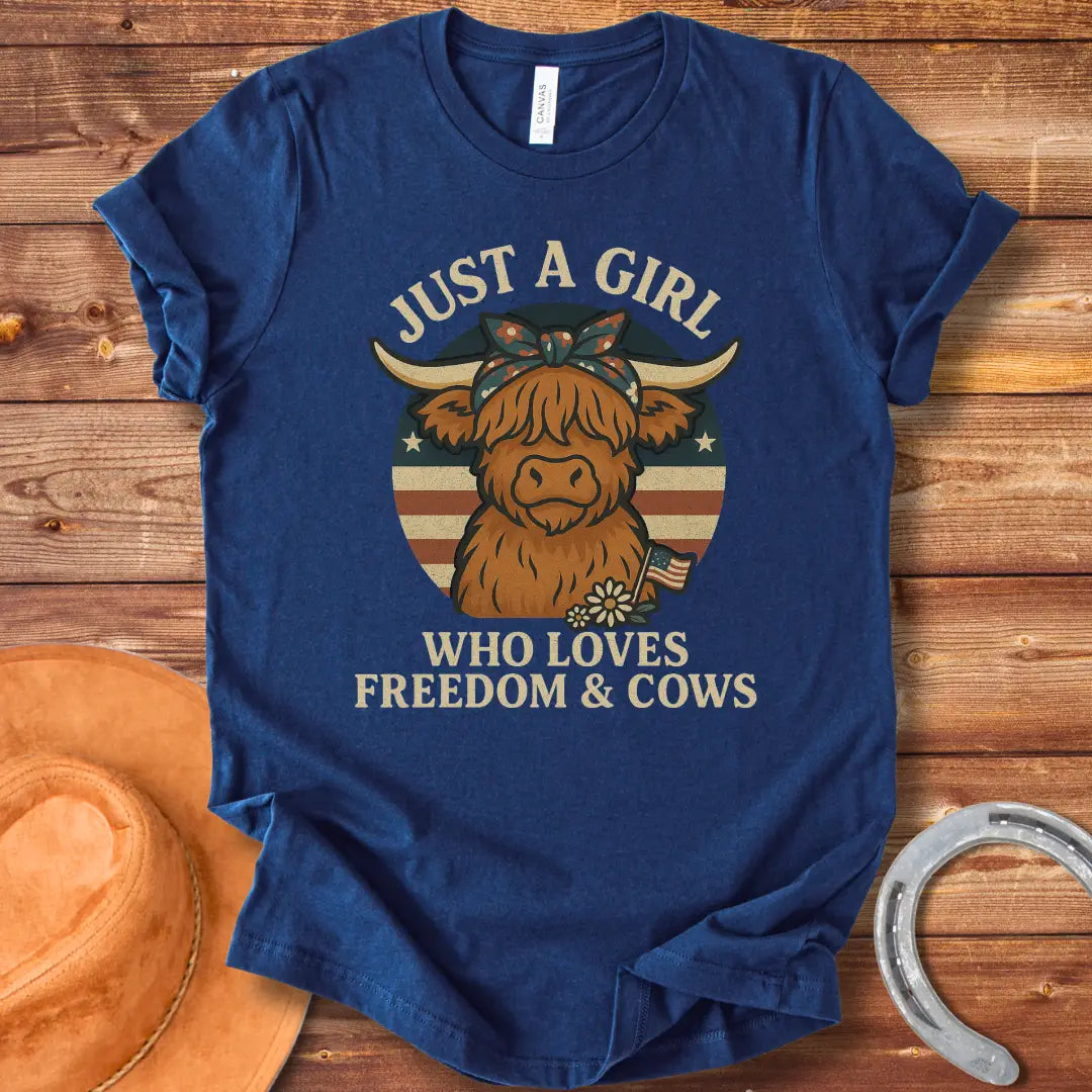 A cute Highland cow wearing a floral bandana, set against a patriotic American flag circle. Text reads 'Just a girl who loves freedom & cows'.