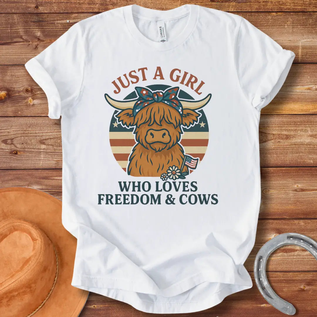 A cute Highland cow wearing a floral bandana, set against a patriotic American flag circle. Text reads 'Just a girl who loves freedom & cows'.