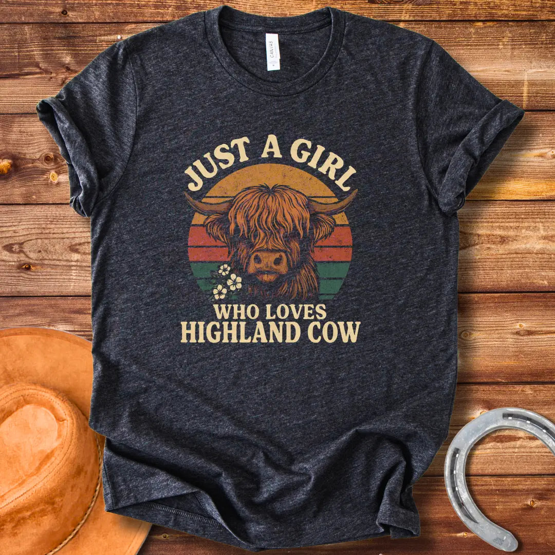 Vintage t-shirt featuring a Highland cow with flowers and the text 'Just a Girl Who Loves Highland Cow' against a retro sunset backdrop.