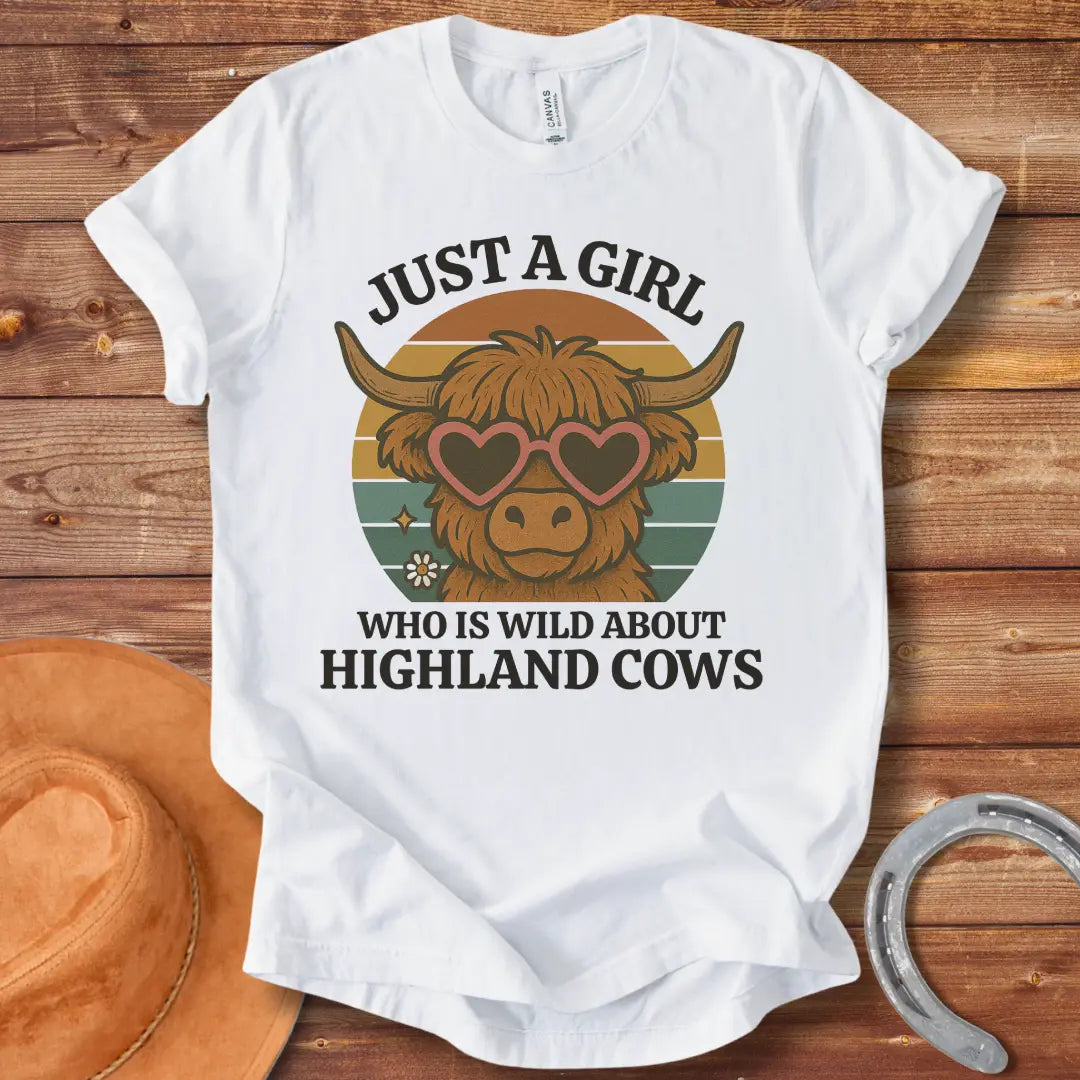 Girl Wild About Highland Cows t-shirt design featuring a Highland cow wearing heart-shaped sunglasses against a sunset backdrop.