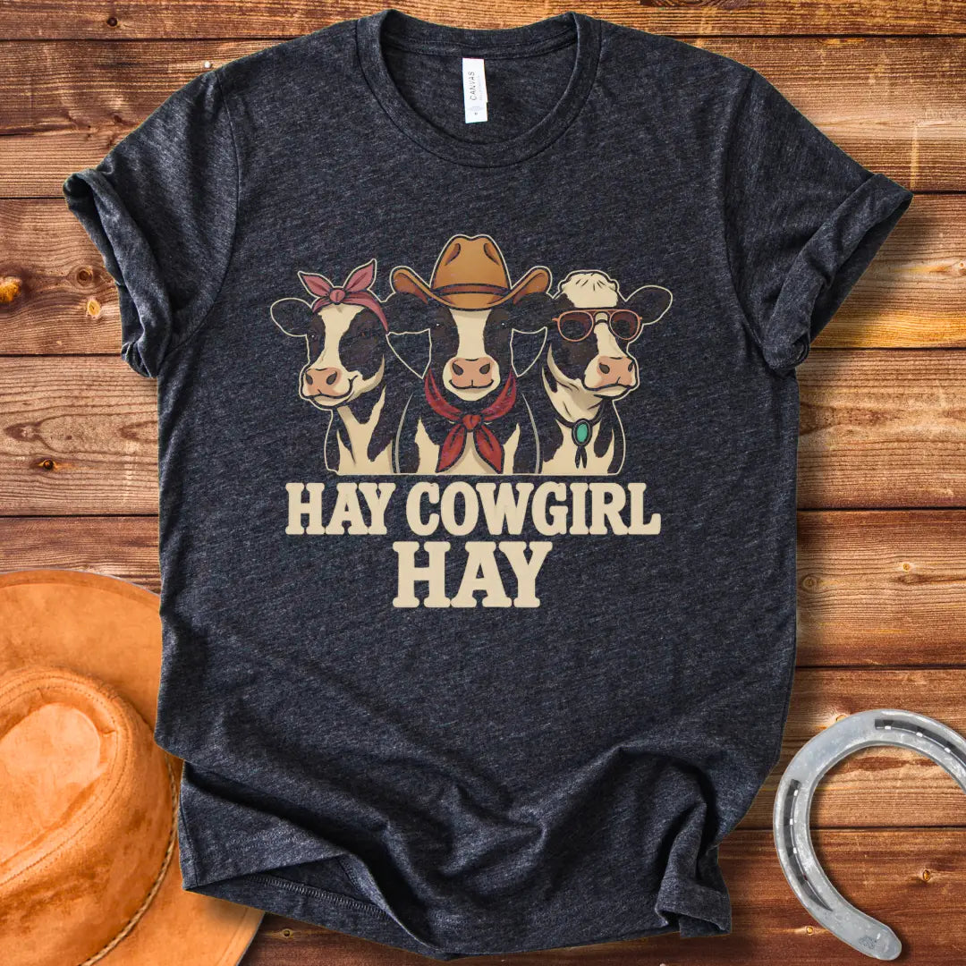 Three cartoon cows, one with a bandana, one with a cowboy hat and scarf, and one with sunglasses, with the text 'Hay Cow Girl Hay' below.