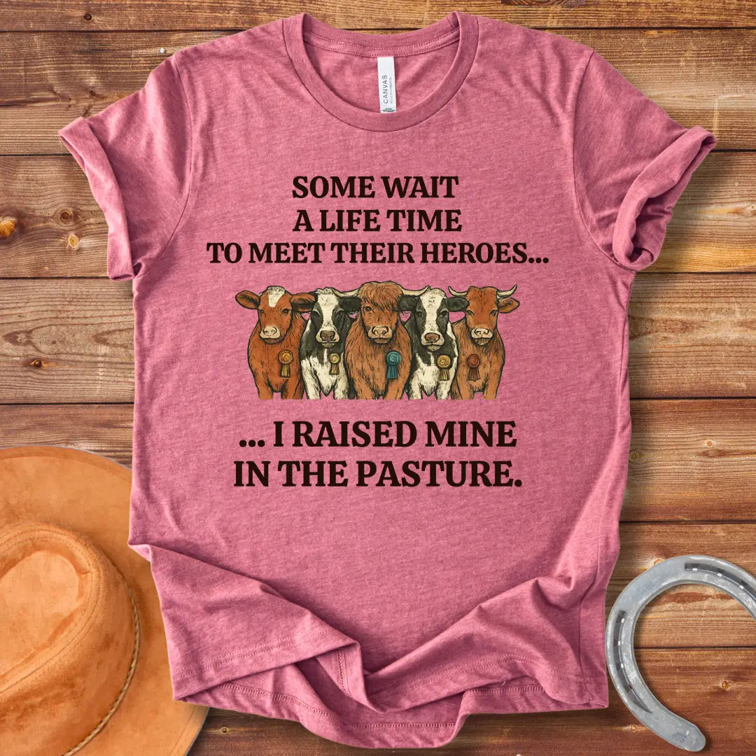 Heroes In The Pasture T-Shirt featuring five cows with ribbons, text saying 'Some wait a lifetime to meet their heroes... I raised mine in the pasture.'