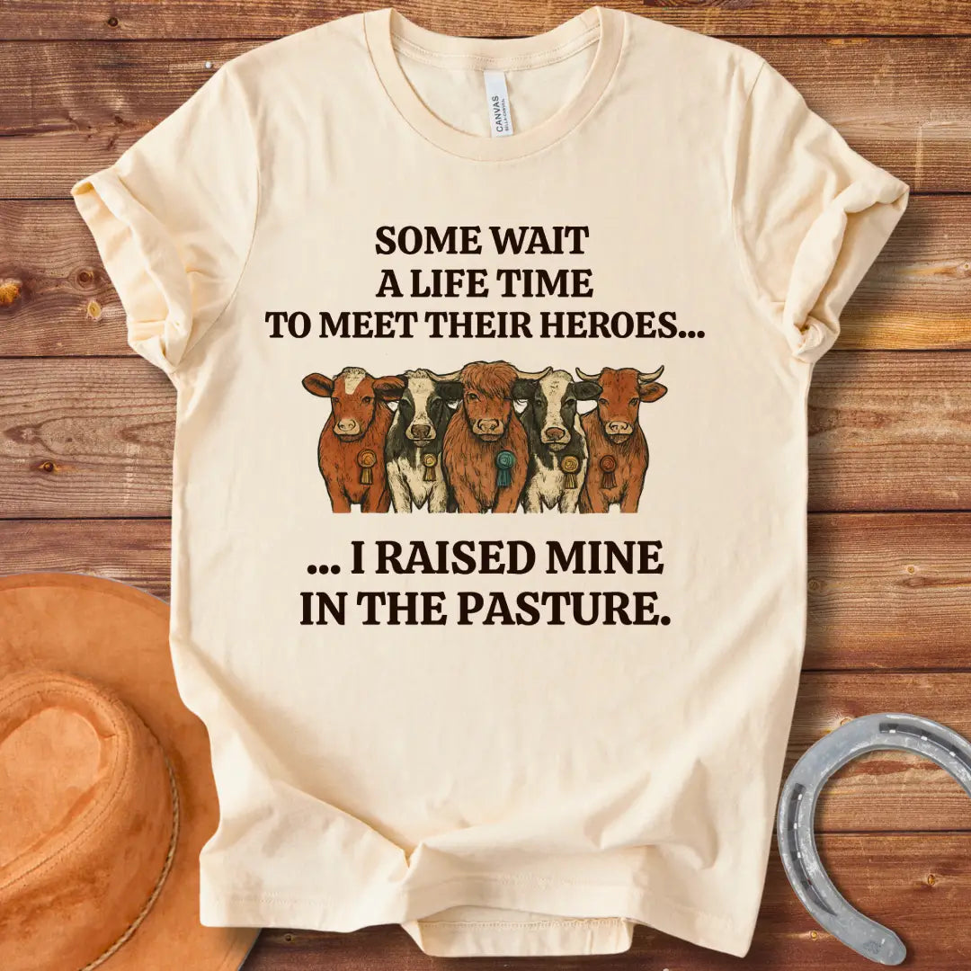 Heroes In The Pasture T-Shirt featuring five cows with ribbons, text saying 'Some wait a lifetime to meet their heroes... I raised mine in the pasture.'