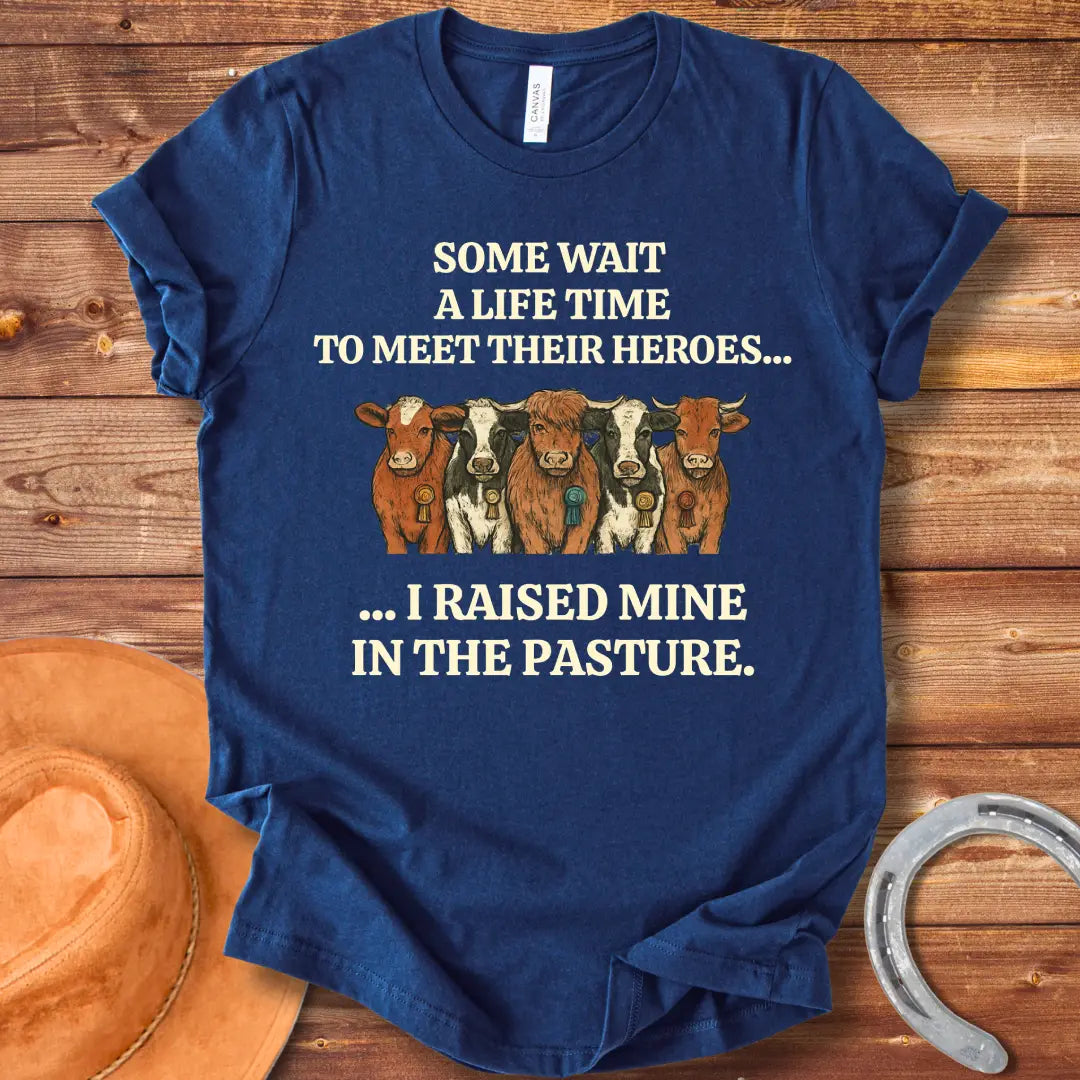 Heroes In The Pasture T-Shirt featuring five cows with ribbons, text saying 'Some wait a lifetime to meet their heroes... I raised mine in the pasture.'