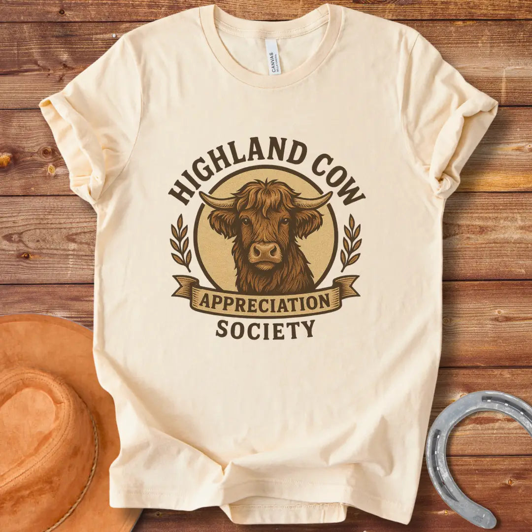Highland Cow Appreciation Society T-Shirt featuring a detailed drawing of a highland cow with the words 'Highland Cow Appreciation Society' in a circular design.