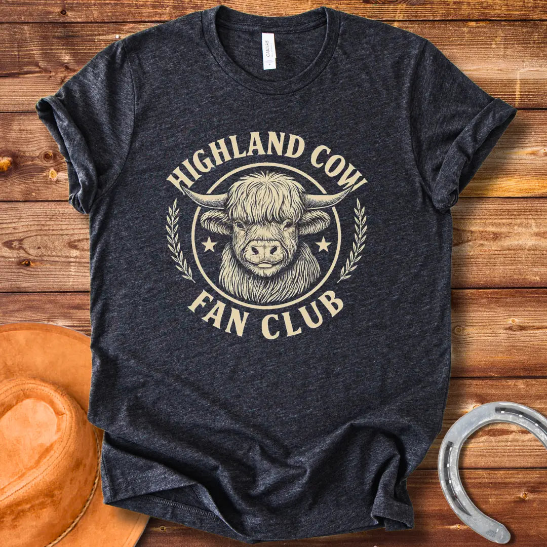 Highland Cow Fan Club T-Shirt featuring a smiling Highland cow in a circular design with text.