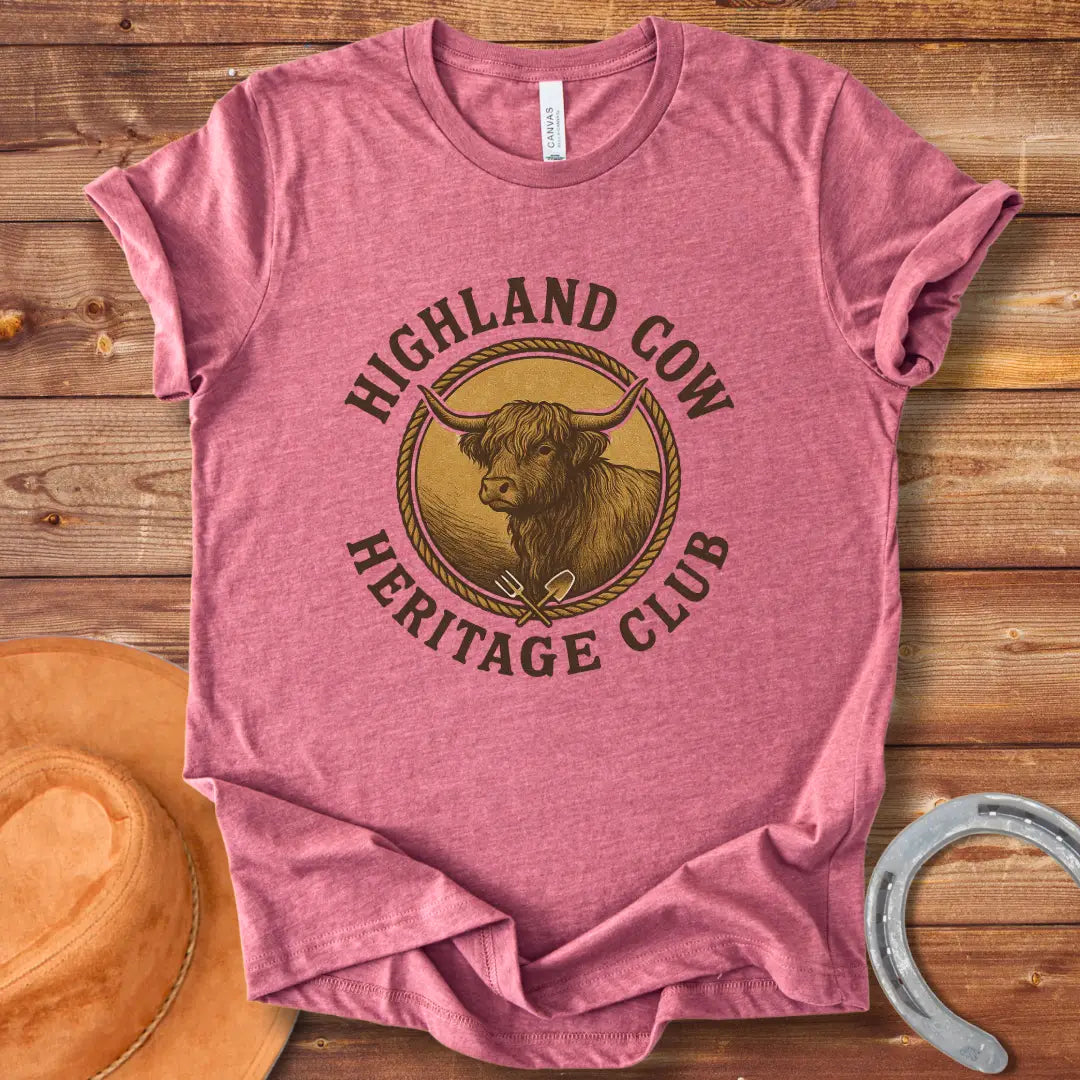 Highland Cow Heritage Club T-Shirt featuring a detailed illustration of a Highland cow with a rope circle and farm tools.