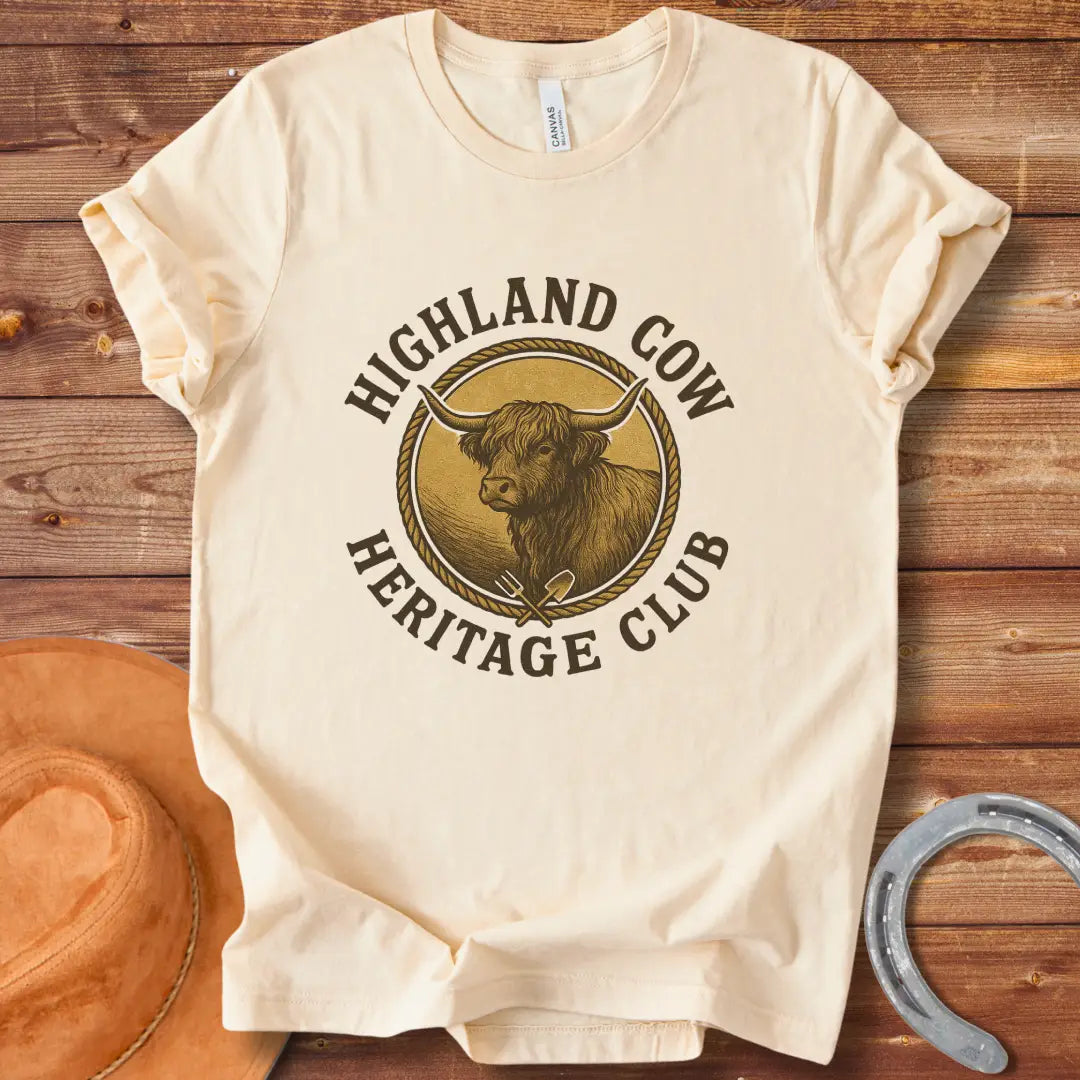 Highland Cow Heritage Club T-Shirt featuring a detailed illustration of a Highland cow with a rope circle and farm tools.