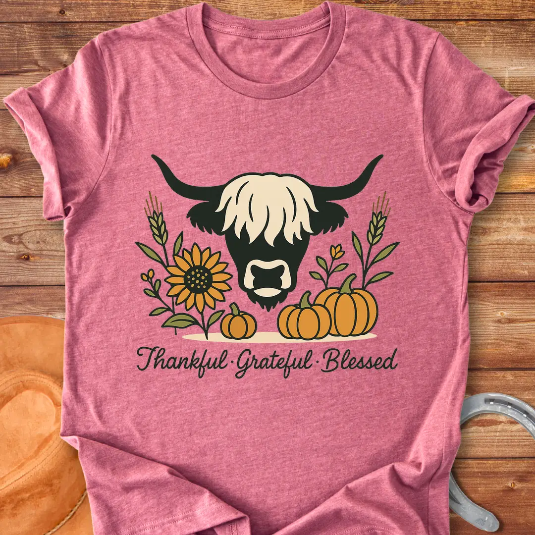 Highland cow with pumpkins, sunflower, and fall harvest design. Text reads: Thankful, Grateful, Blessed. Cow Lovers Clothing.