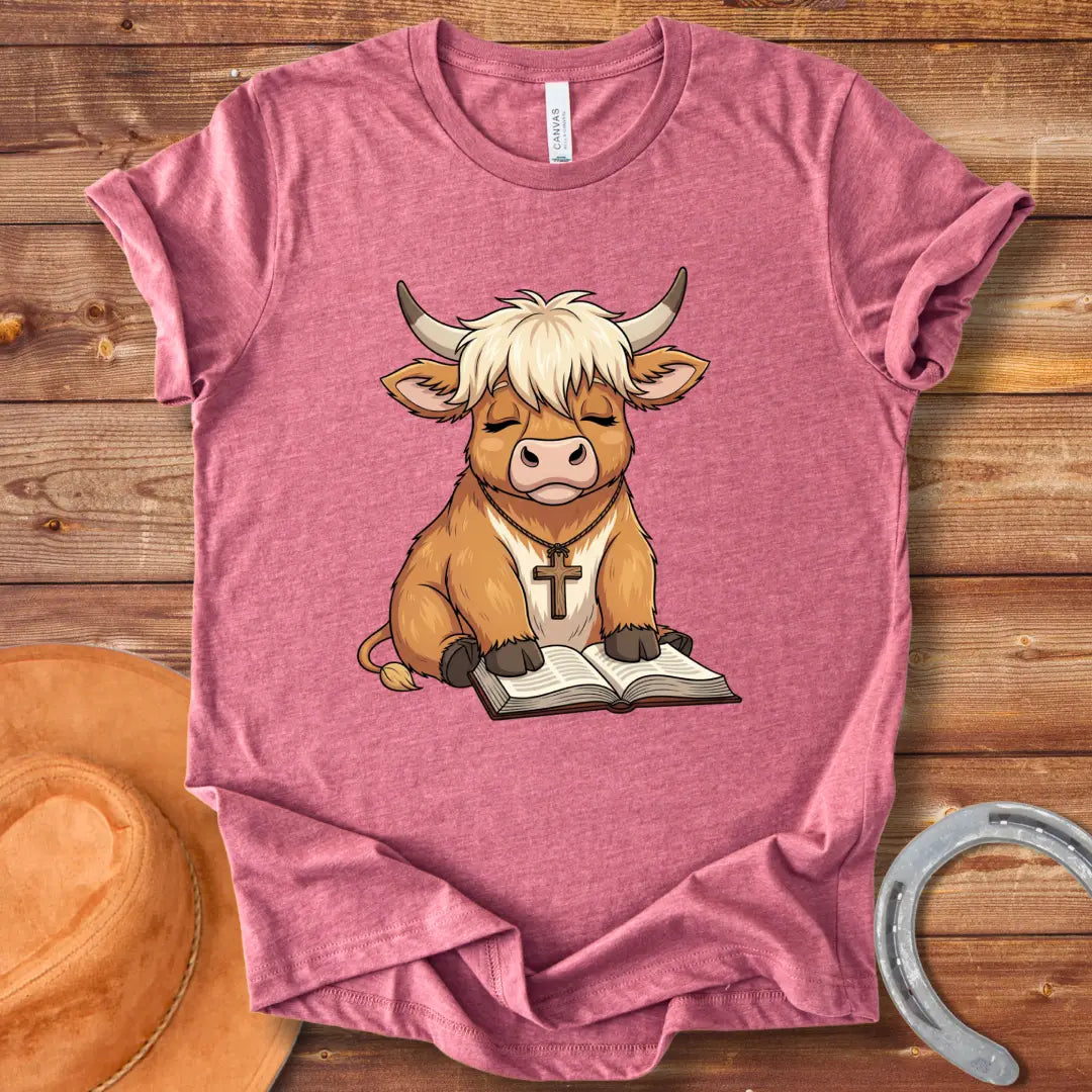 Cartoon illustration of a cow wearing a cross necklace, sitting peacefully with a book open in its lap.