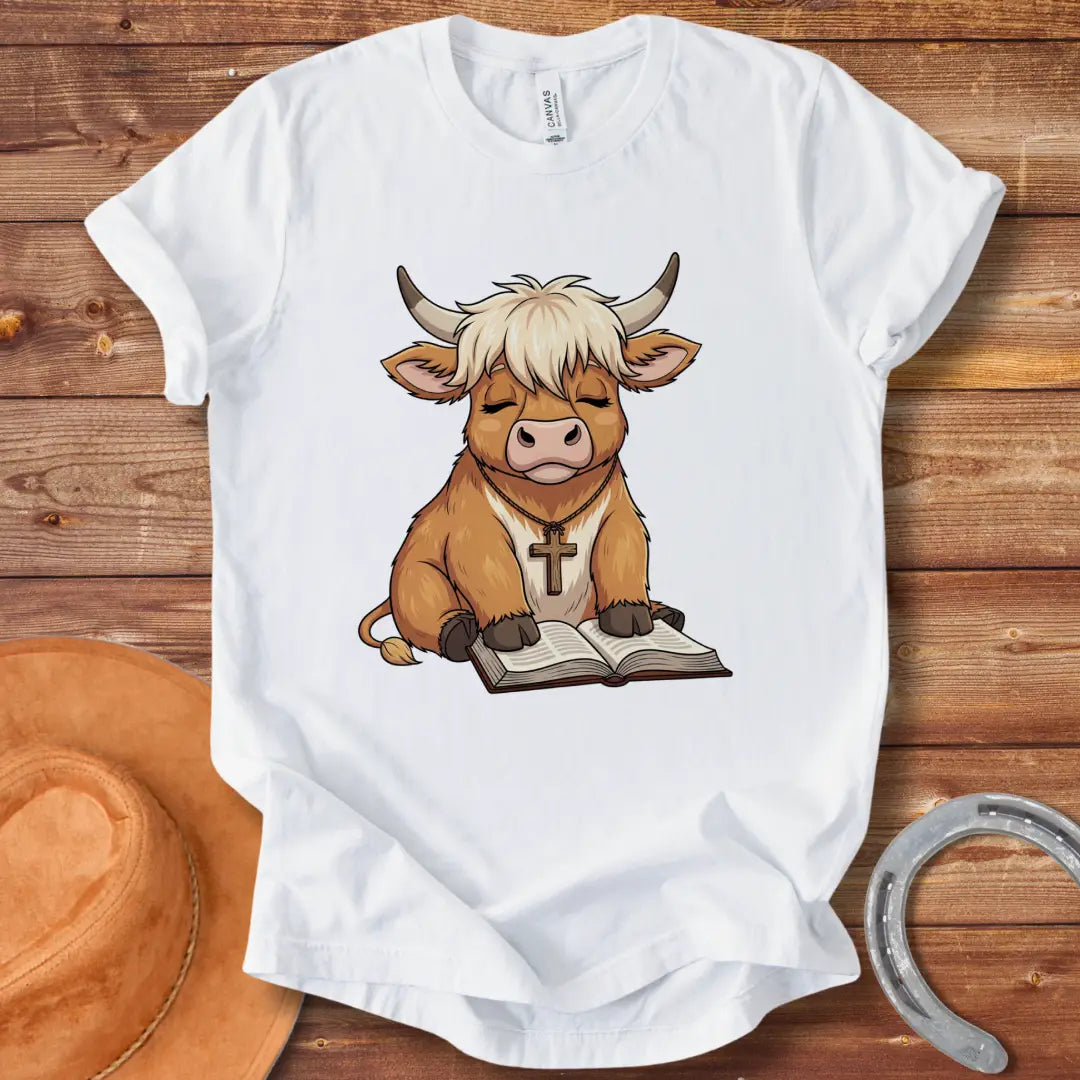 Cartoon illustration of a cow wearing a cross necklace, sitting peacefully with a book open in its lap.