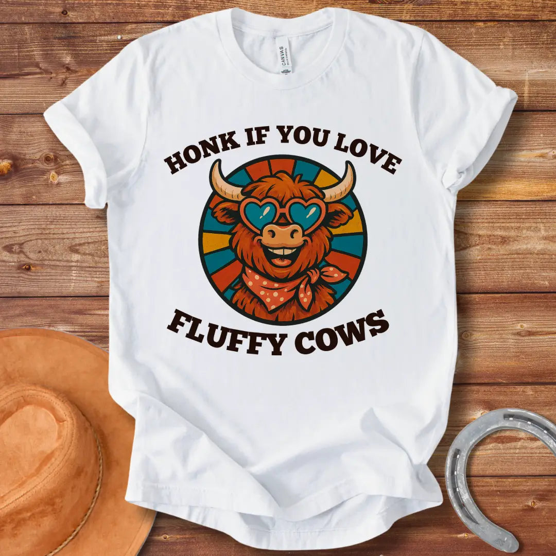 T-shirt design with a smiling cow wearing heart-shaped sunglasses and a bandana, with the text 'Honk If You Love Fluffy Cows'.