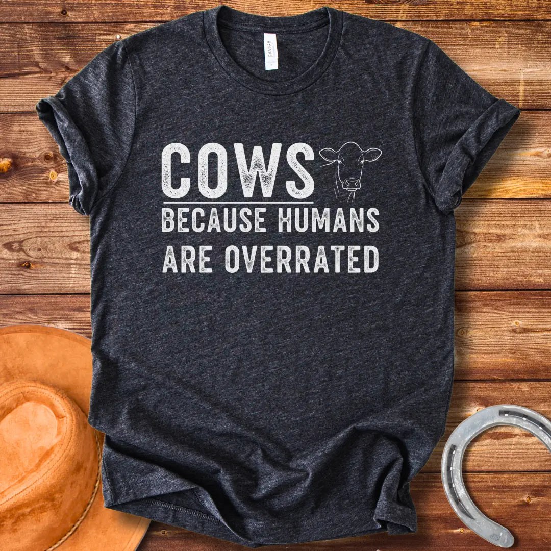A black and white graphic t-shirt design that reads 'COWS BECAUSE HUMANS ARE OVERRATED' with a simple cow illustration.