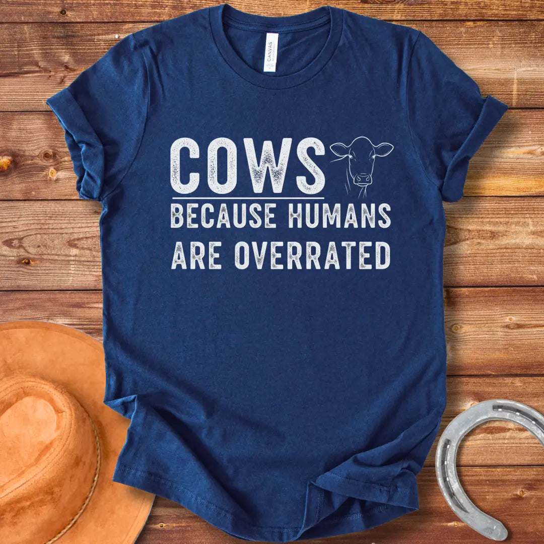 A black and white graphic t-shirt design that reads 'COWS BECAUSE HUMANS ARE OVERRATED' with a simple cow illustration.