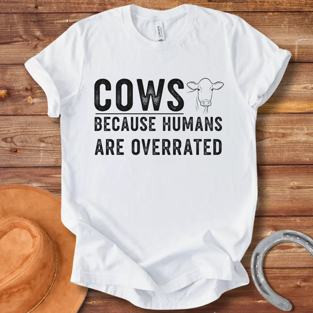 A black and white graphic t-shirt design that reads 'COWS BECAUSE HUMANS ARE OVERRATED' with a simple cow illustration.
