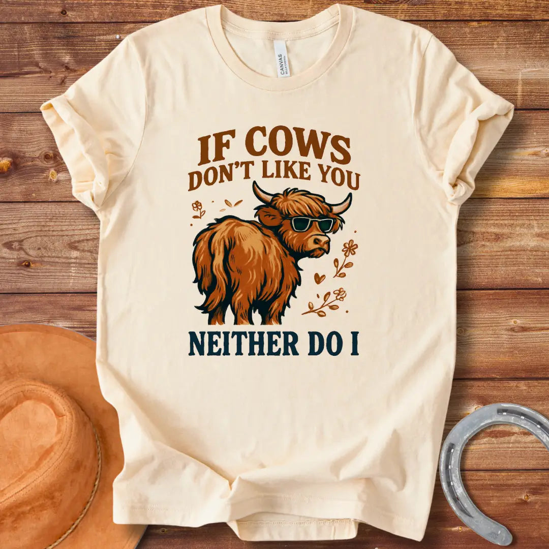 T-shirt design featuring a cool cow wearing sunglasses with the text 'If Cows Don't Like You Neither Do I' in brown and blue font on a black background.