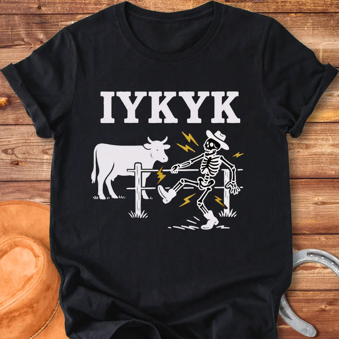 Funny graphic tee featuring a skeleton getting shocked by an electric fence with a cow in the background.