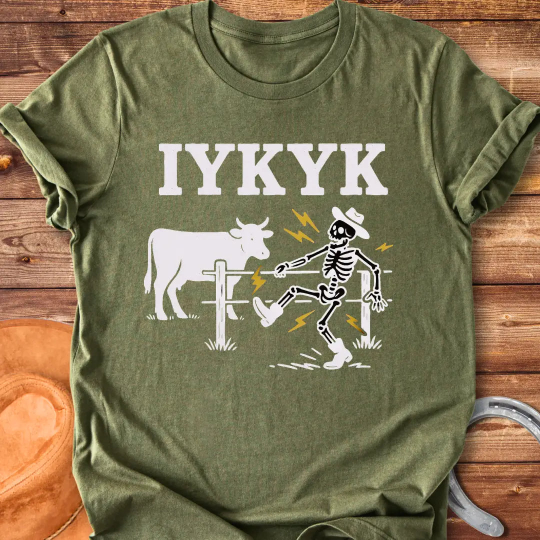 Funny graphic tee featuring a skeleton getting shocked by an electric fence with a cow in the background.