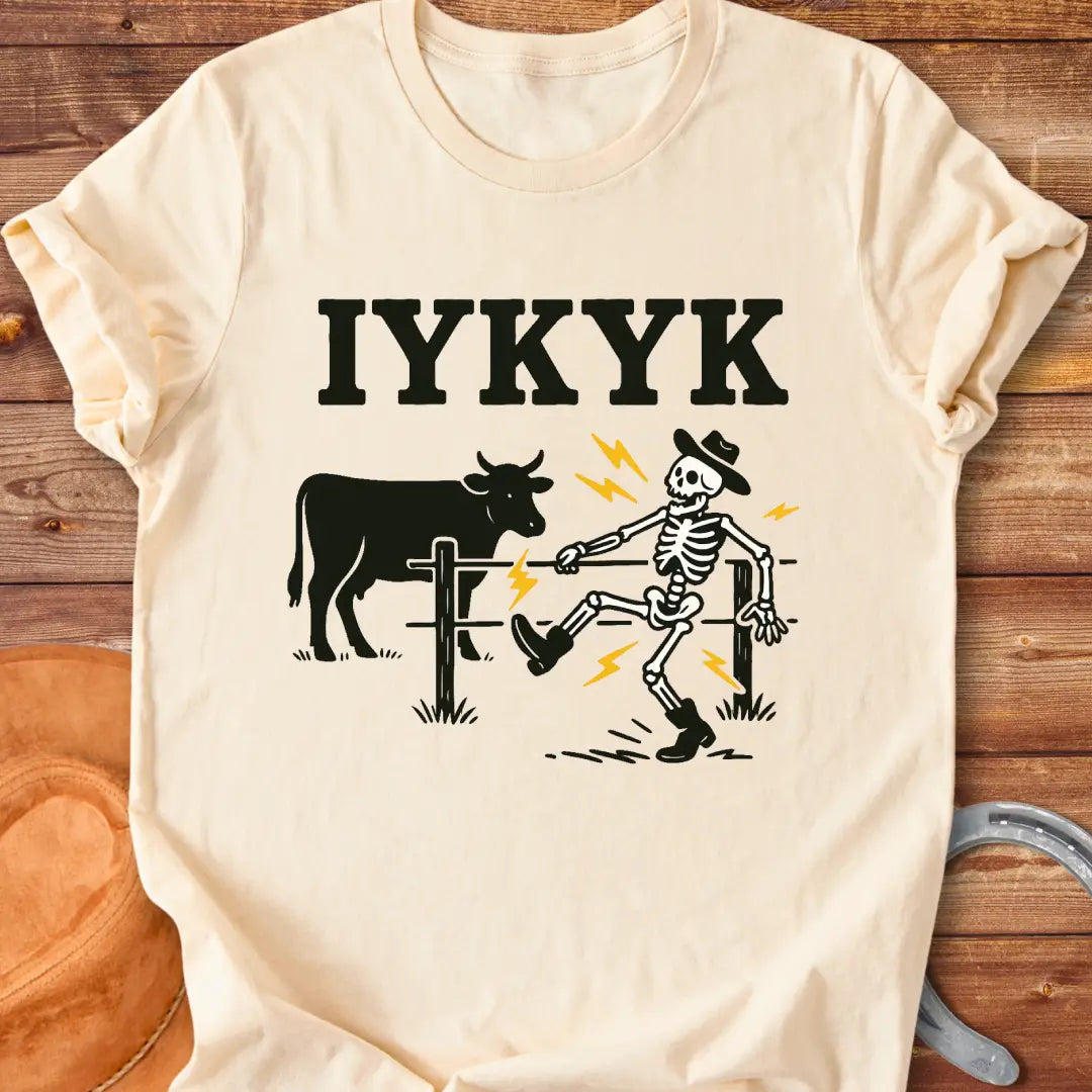 Funny graphic tee featuring a skeleton getting shocked by an electric fence with a cow in the background.