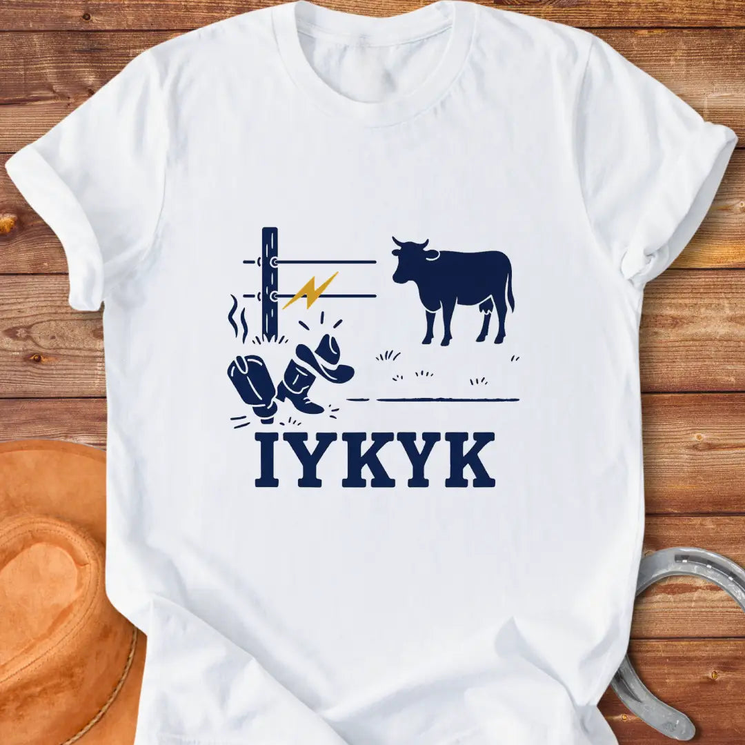 Graphic design on a t-shirt depicts a shocked cowboy hat and boots with a hot wire and a cow in the background, with the words IYKYK at the bottom
