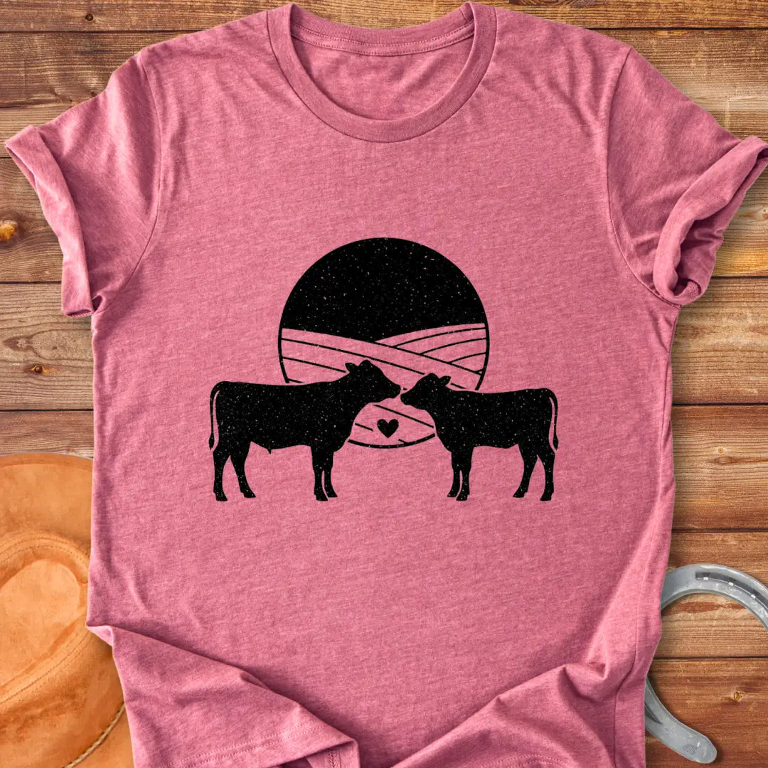 Silhouette of a mother cow and her calf, with a heart in between them and a field background
