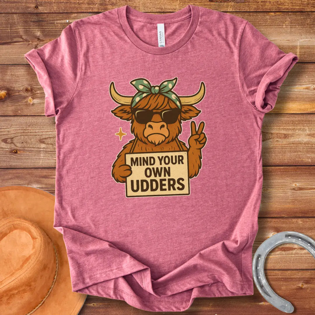 Illustration of a cool cow wearing sunglasses and a bandana, holding a sign that says 'Mind Your Own Udders' and giving a peace sign.