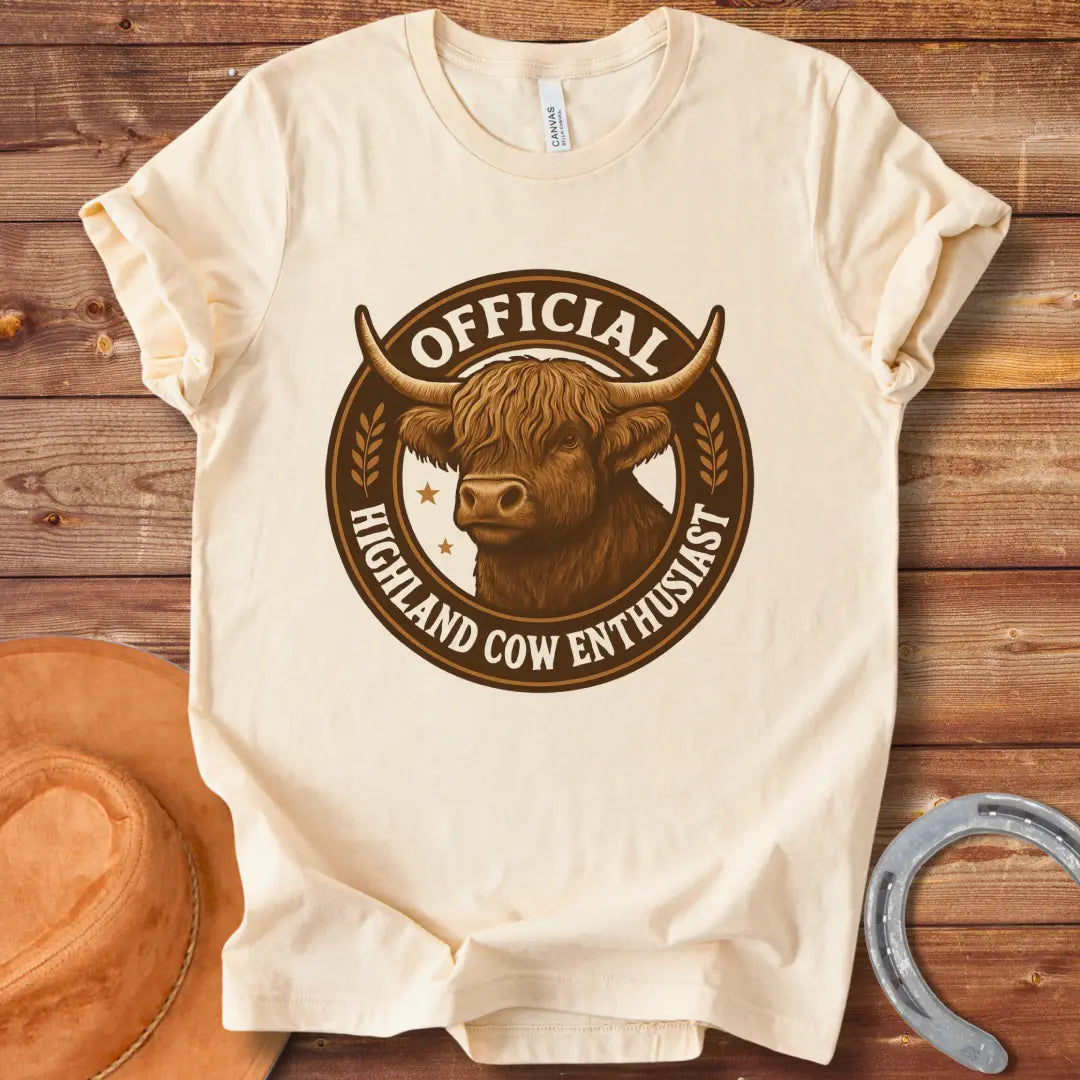 Official Highland Cow Enthusiast T-Shirt design featuring a detailed illustration of a Highland cow's head within a circular emblem with the words 'Official Highland Cow Enthusiast' written on it.