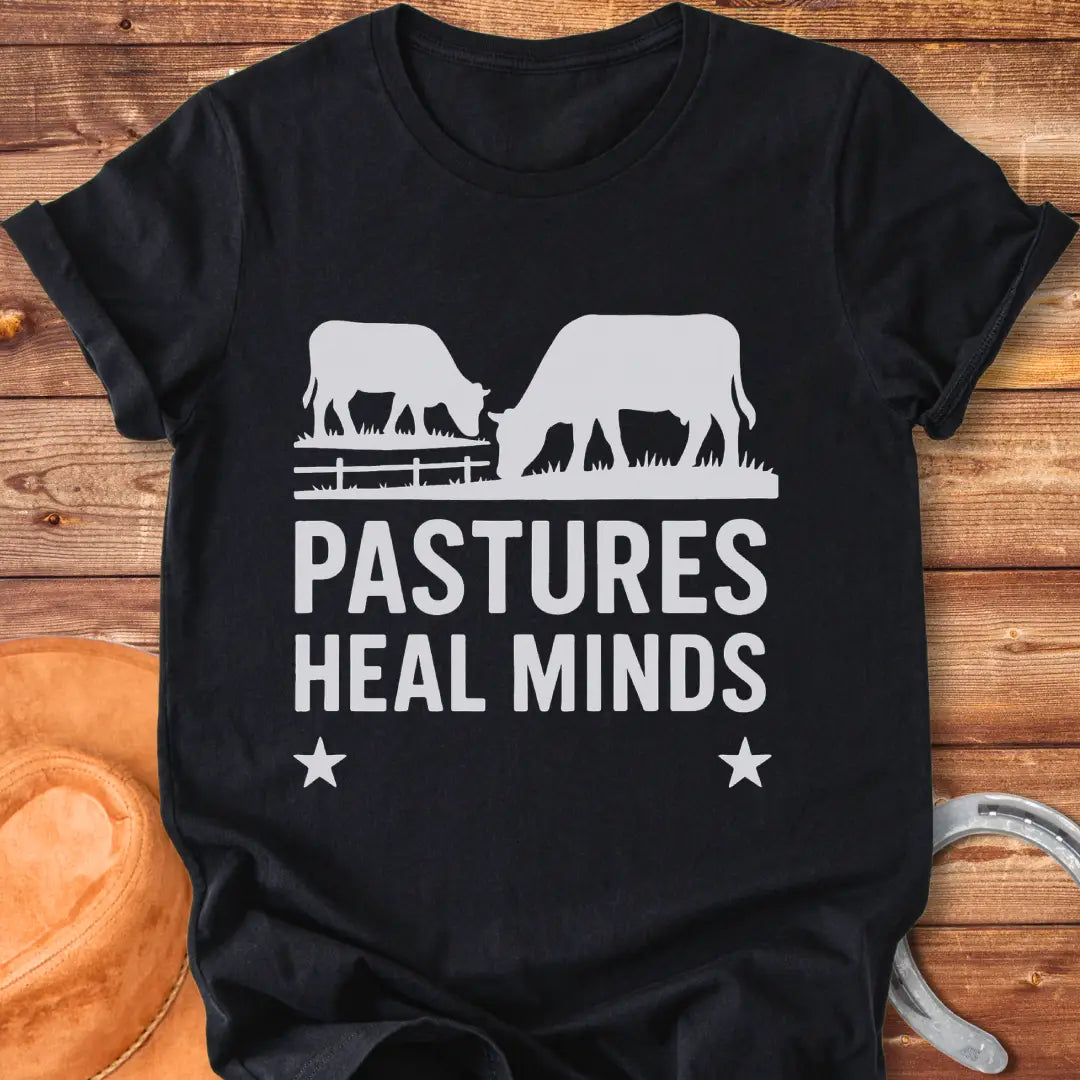 Two cows grazing in a pasture with the text 'Pastures Heal Minds' in a unique design.