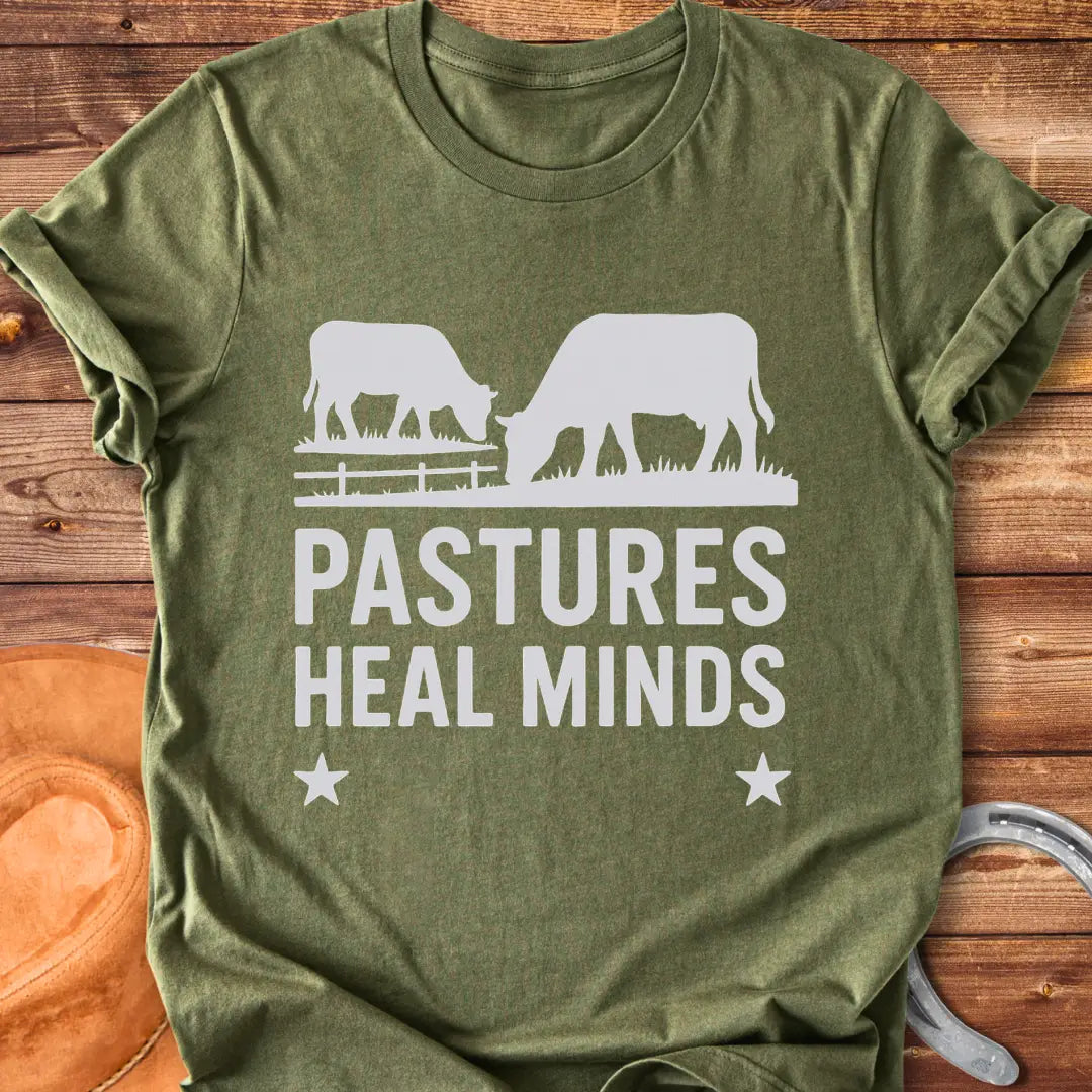 Two cows grazing in a pasture with the text 'Pastures Heal Minds' in a unique design.