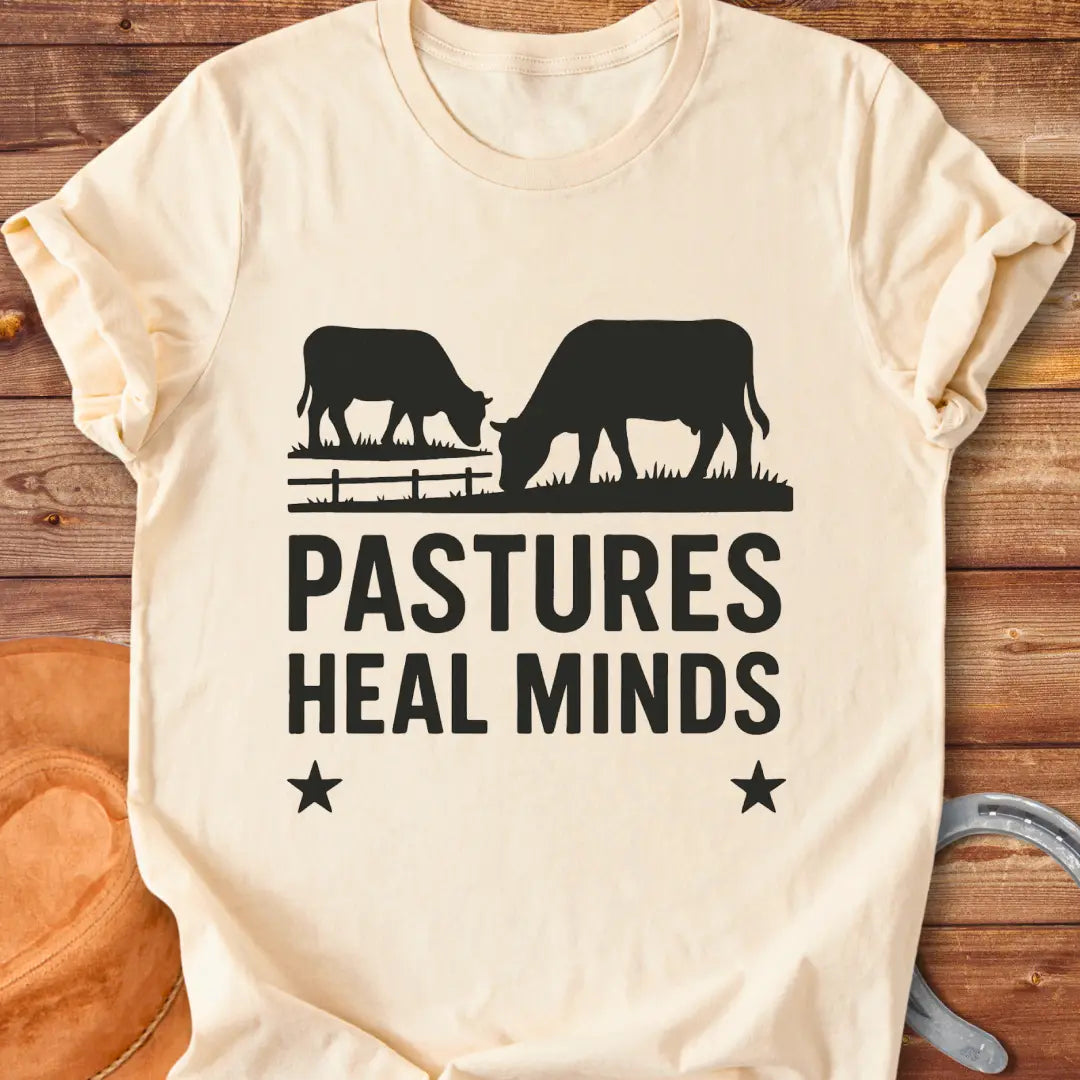 Two cows grazing in a pasture with the text 'Pastures Heal Minds' in a unique design.
