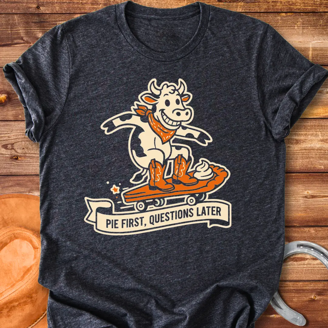 T-shirt design featuring a cow riding a pie skateboard with the words 'Pie First, Questions Later'.