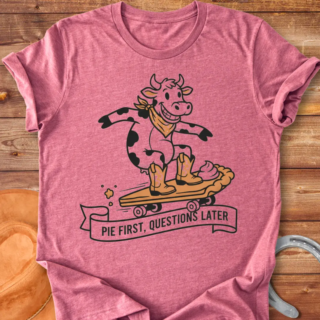 T-shirt design featuring a cow riding a pie skateboard with the words 'Pie First, Questions Later'.