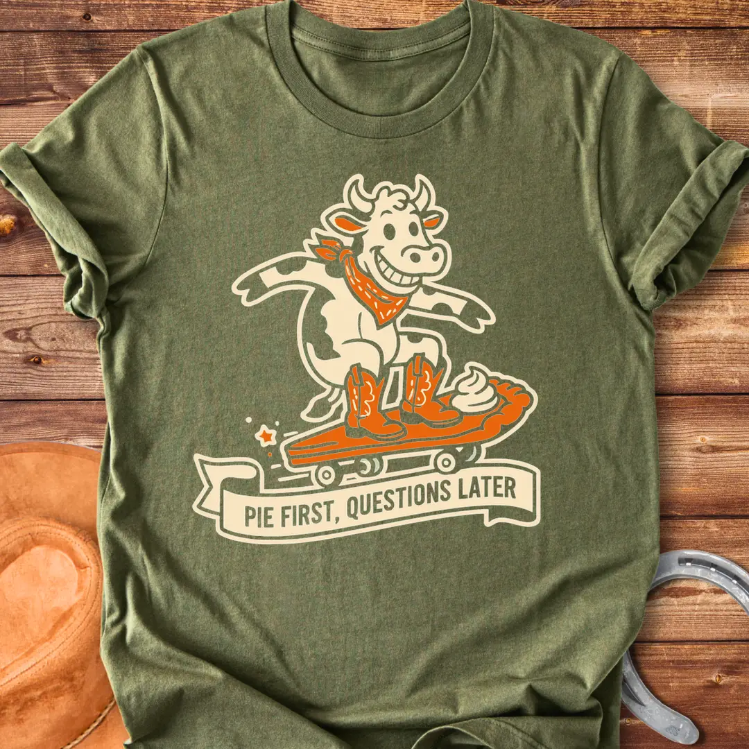 T-shirt design featuring a cow riding a pie skateboard with the words 'Pie First, Questions Later'.