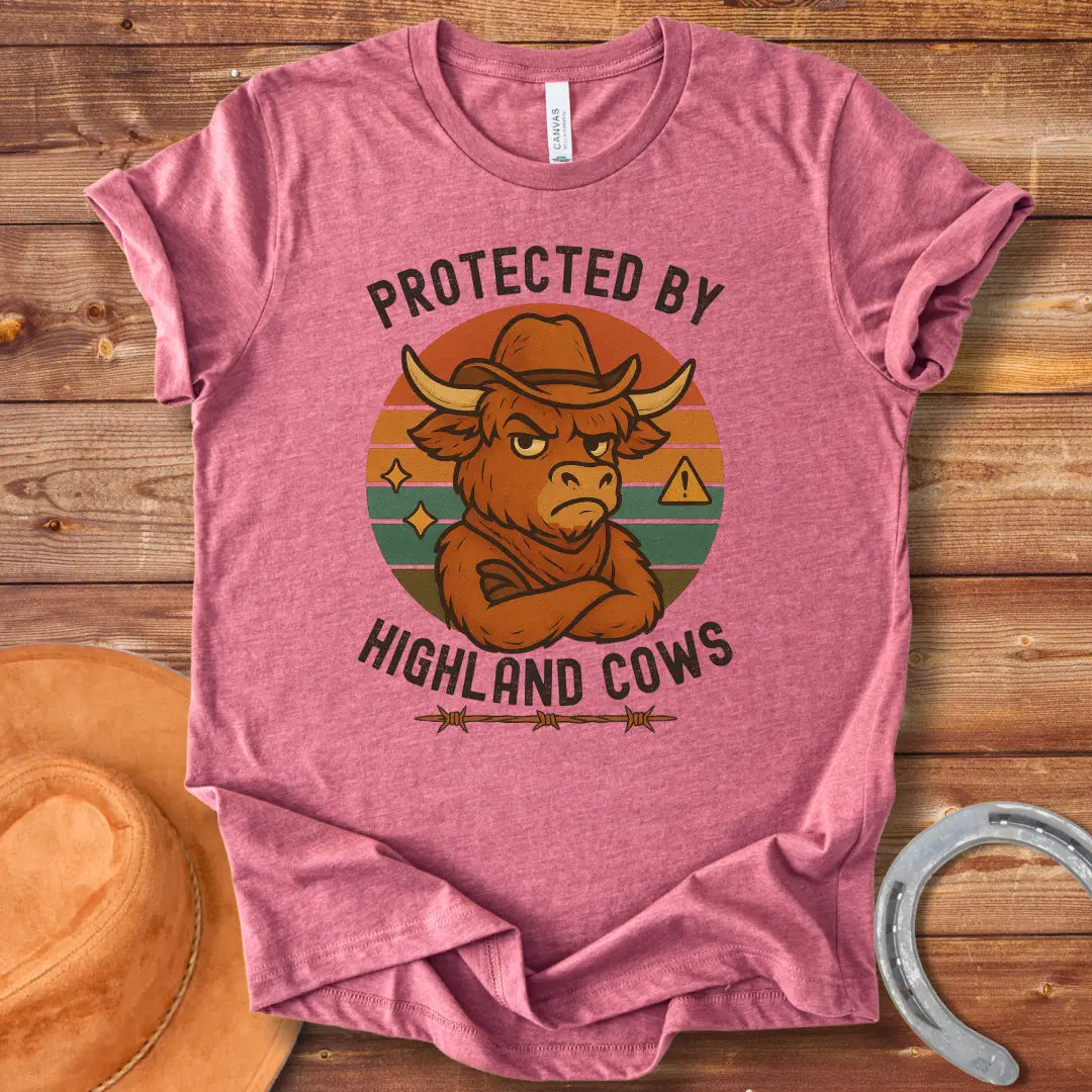 Protected by Highland Cows t-shirt featuring a cartoon Highland cow wearing a cowboy hat with a stern look.