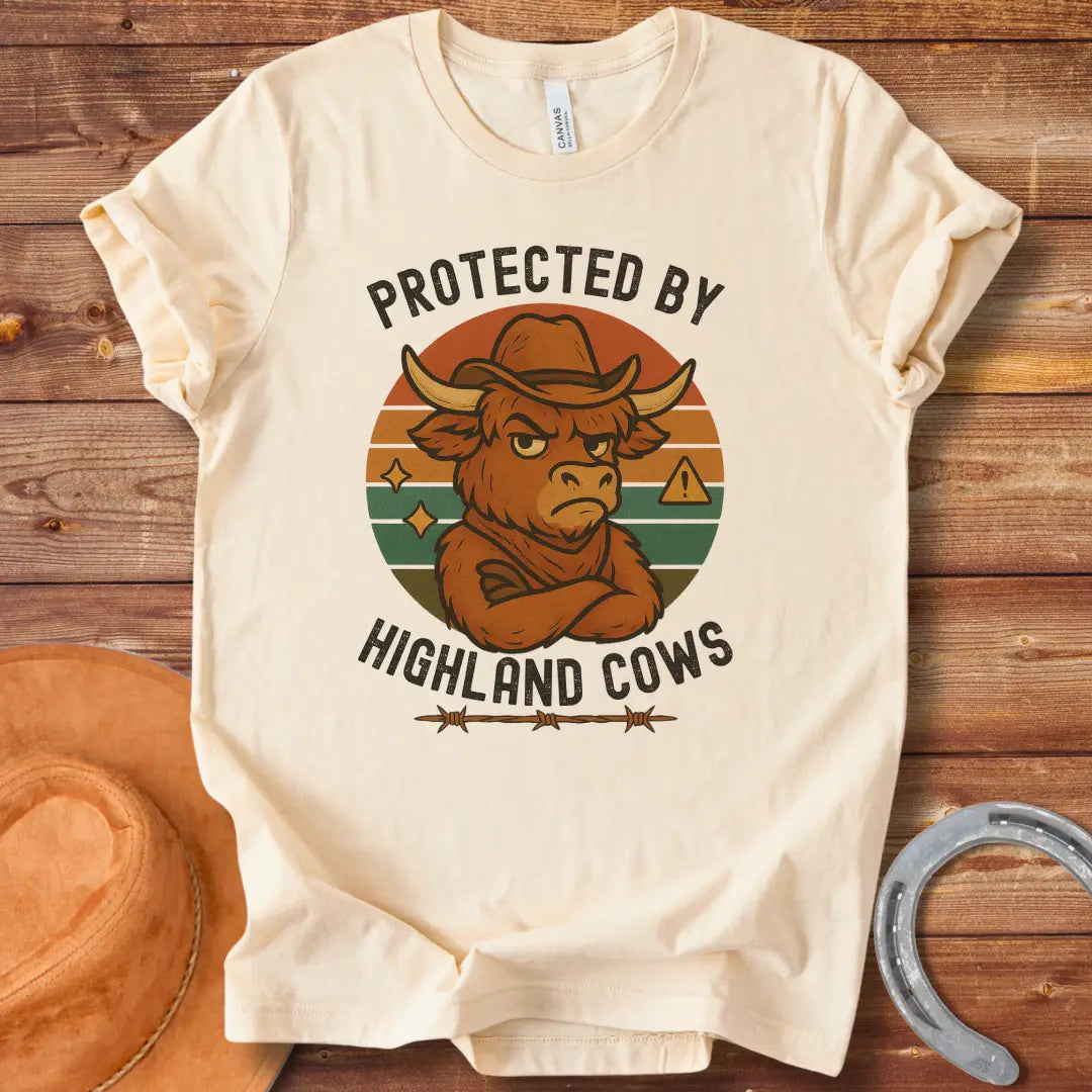 Protected by Highland Cows t-shirt featuring a cartoon Highland cow wearing a cowboy hat with a stern look.